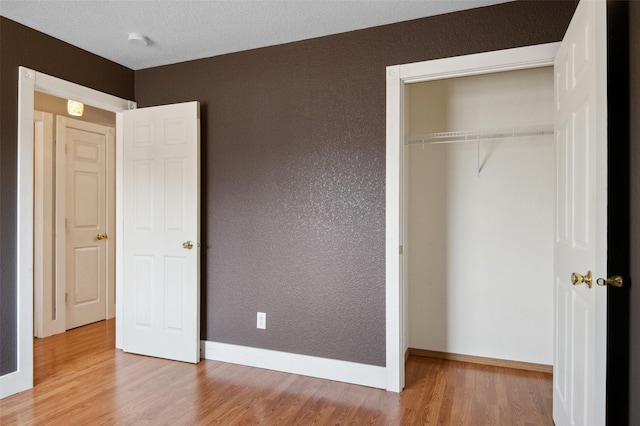 unfurnished bedroom featuring a textured ceiling, hardwood / wood-style flooring, and a closet