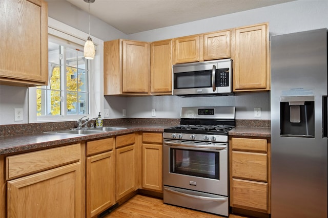 kitchen with light wood-type flooring, stainless steel appliances, sink, pendant lighting, and light brown cabinets