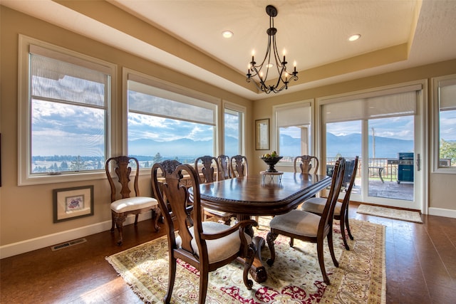 dining room with a mountain view, a raised ceiling, and an inviting chandelier