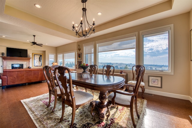 dining room featuring ceiling fan with notable chandelier, a healthy amount of sunlight, and a tray ceiling