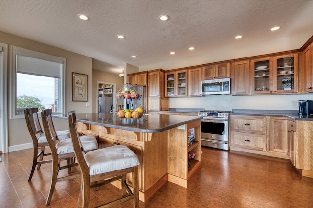 kitchen with a breakfast bar area, a kitchen island, a textured ceiling, and appliances with stainless steel finishes