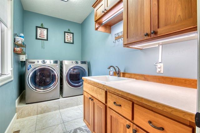 clothes washing area with cabinets, a textured ceiling, sink, separate washer and dryer, and light tile patterned flooring