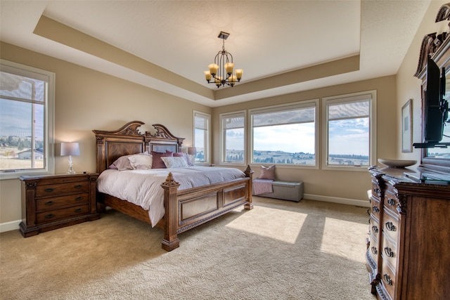 carpeted bedroom featuring a raised ceiling and an inviting chandelier