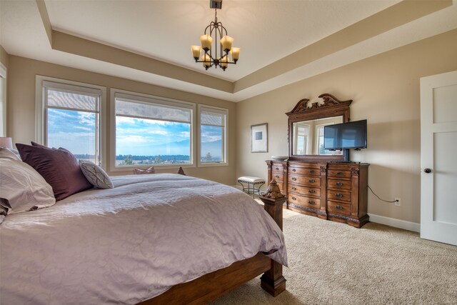 bedroom featuring a raised ceiling, carpet floors, and a chandelier