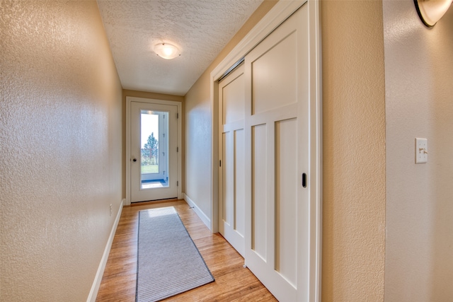 doorway featuring a textured ceiling and light hardwood / wood-style flooring