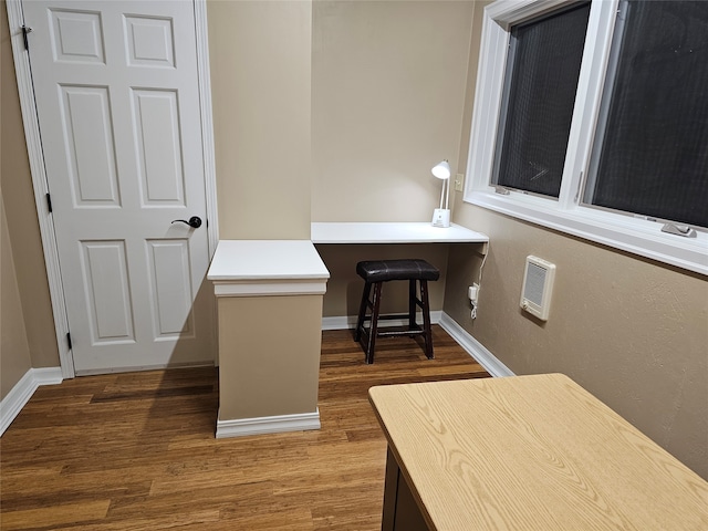 home office featuring hardwood / wood-style flooring, built in desk, and heating unit