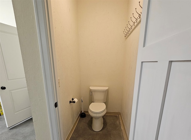 bathroom with concrete flooring and toilet