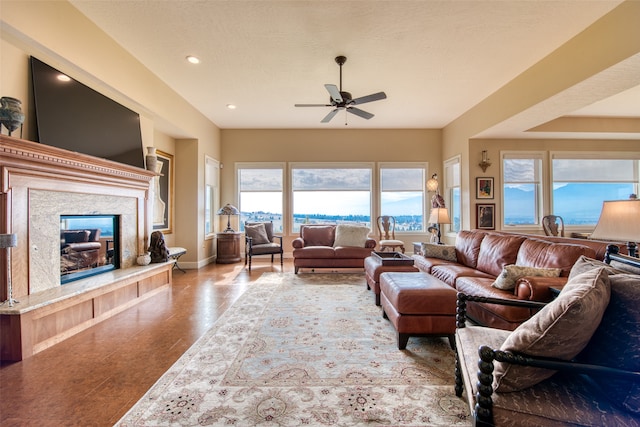 living room with ceiling fan, a high end fireplace, and a healthy amount of sunlight