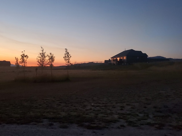 yard at dusk featuring a rural view