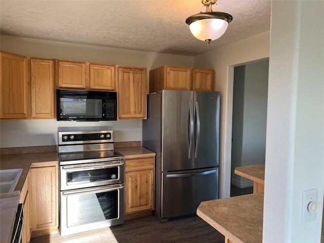 kitchen with a textured ceiling, stainless steel appliances, and dark hardwood / wood-style floors