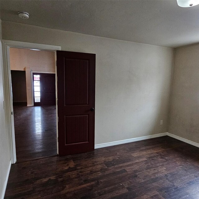 empty room with dark hardwood / wood-style flooring