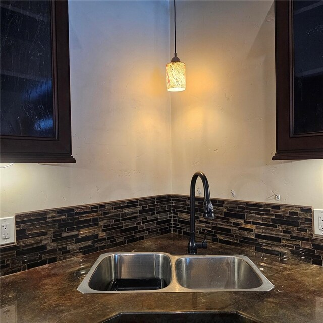 kitchen with sink, tasteful backsplash, hanging light fixtures, and dark brown cabinetry