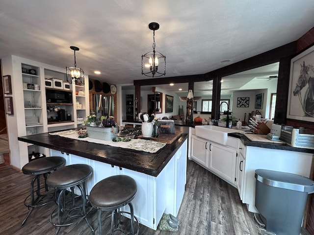 kitchen featuring white cabinets, a kitchen island, hanging light fixtures, and a breakfast bar area