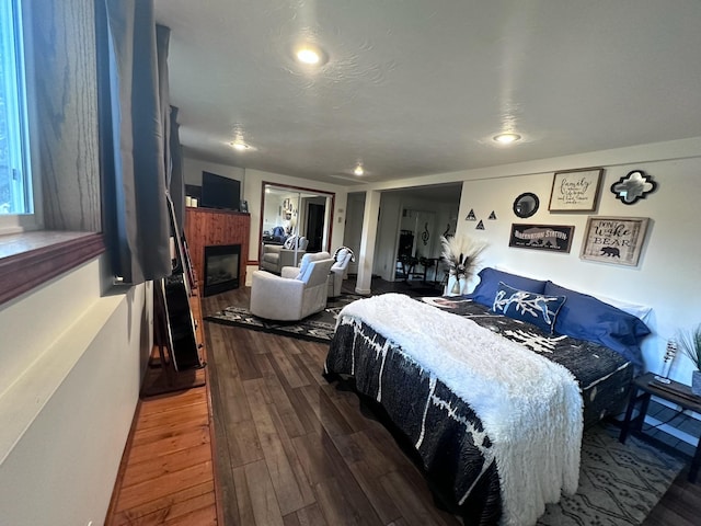 bedroom featuring a tile fireplace and hardwood / wood-style flooring