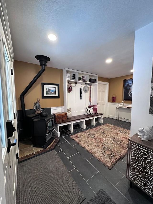 mudroom featuring dark tile patterned flooring, a wood stove, and a textured ceiling