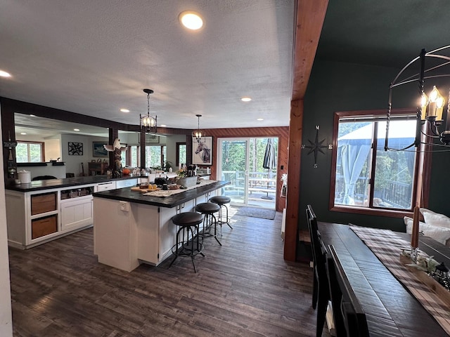 kitchen featuring white cabinets, a breakfast bar, hanging light fixtures, and a healthy amount of sunlight