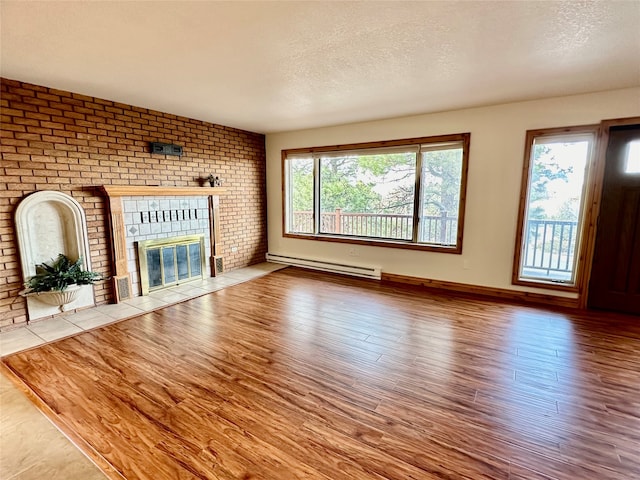 unfurnished living room featuring a baseboard heating unit, a textured ceiling, a fireplace, and light wood-type flooring