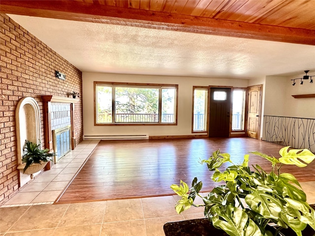 unfurnished living room featuring beam ceiling, brick wall, and light tile patterned flooring