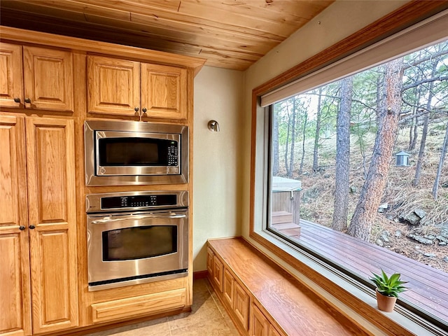 kitchen with light tile patterned floors, baseboards, appliances with stainless steel finishes, and wood ceiling