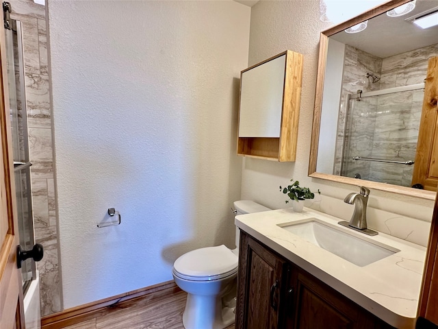 bathroom featuring hardwood / wood-style flooring, toilet, walk in shower, and vanity