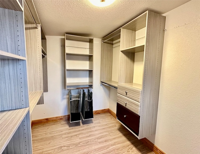walk in closet featuring built in desk and light wood-style flooring