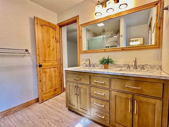 full bathroom featuring double vanity, a textured wall, a sink, and a stall shower