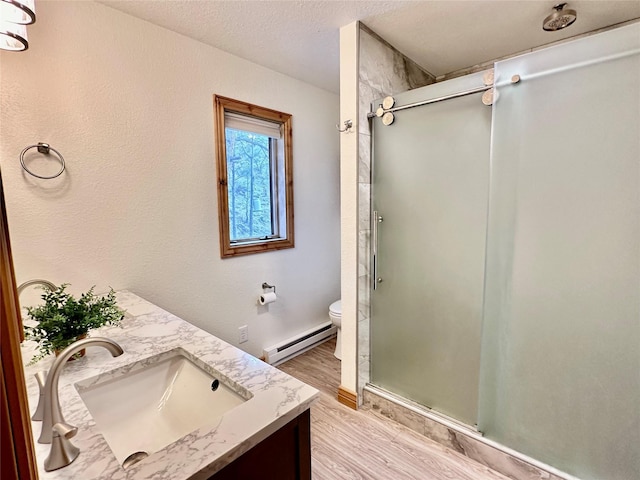 full bathroom with vanity, wood finished floors, toilet, baseboard heating, and a shower stall