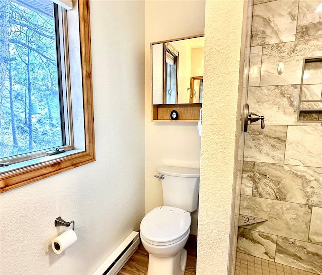bathroom featuring a tile shower, baseboard heating, toilet, baseboards, and wood finished floors