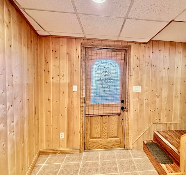 foyer featuring a paneled ceiling and wood walls