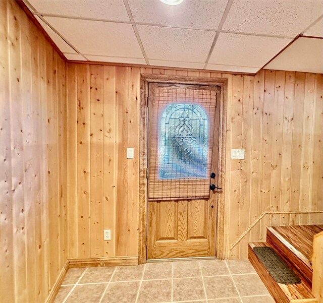 foyer entrance featuring wood walls and a paneled ceiling