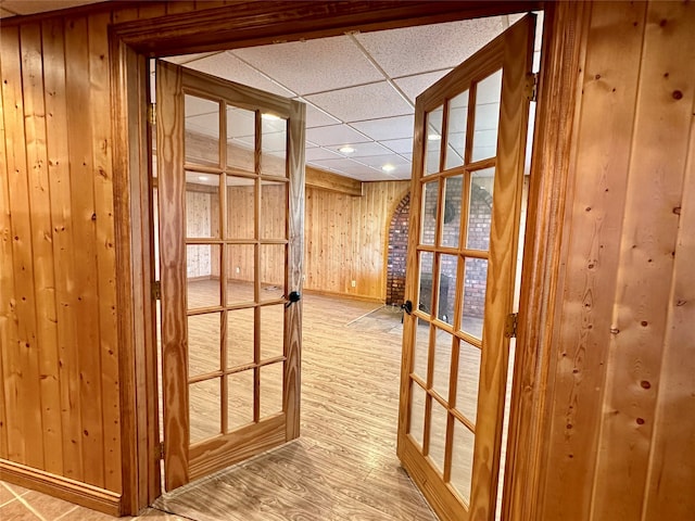 hallway featuring hardwood / wood-style floors, a paneled ceiling, and wood walls