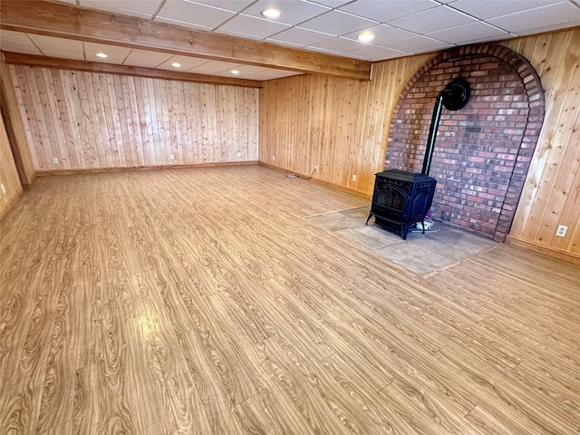 basement featuring baseboards, a wood stove, and wood finished floors