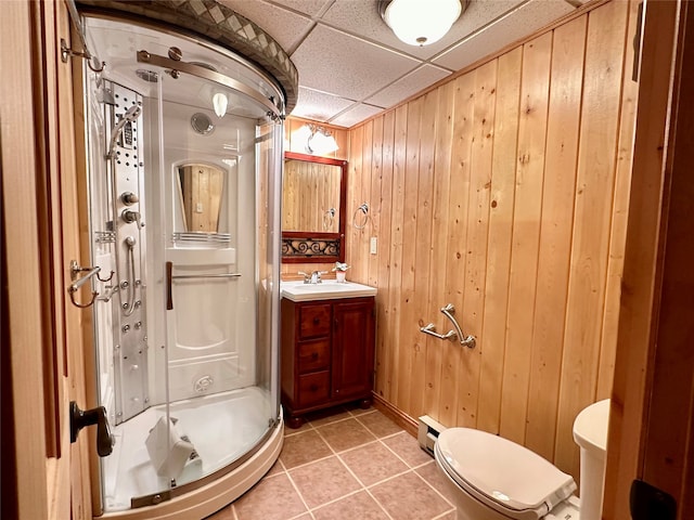 bathroom with a baseboard radiator, vanity, walk in shower, wood walls, and a drop ceiling