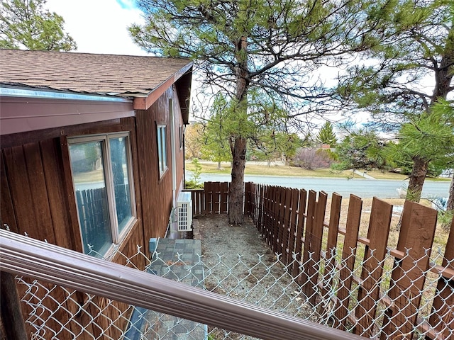 view of side of property featuring fence and roof with shingles