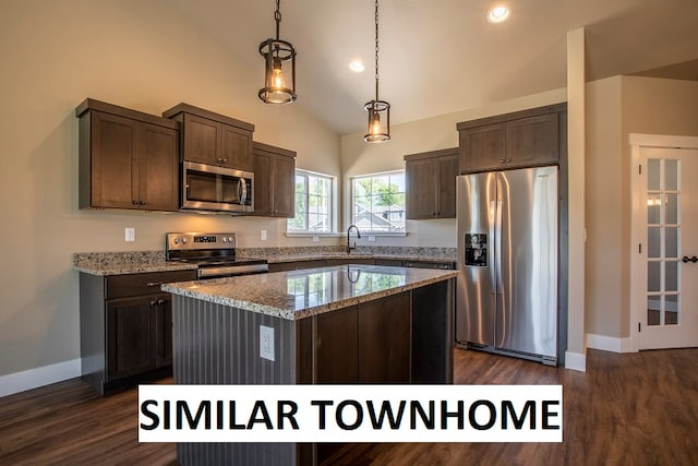 kitchen with appliances with stainless steel finishes, a kitchen island, vaulted ceiling, dark wood-type flooring, and light stone counters