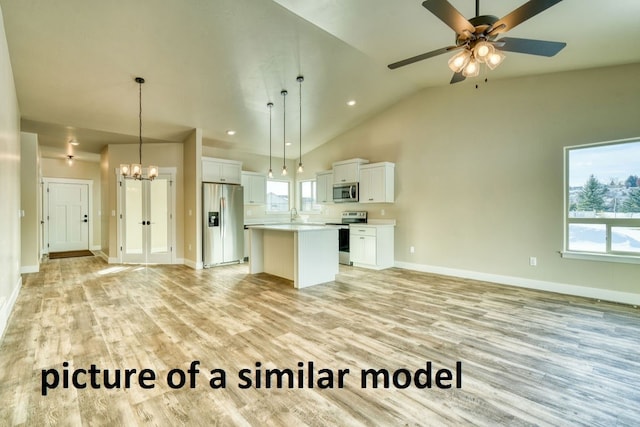 kitchen featuring a kitchen island, white cabinets, vaulted ceiling, decorative light fixtures, and appliances with stainless steel finishes