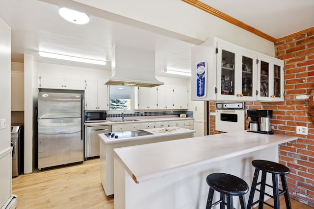 kitchen with kitchen peninsula, appliances with stainless steel finishes, light hardwood / wood-style flooring, white cabinets, and a breakfast bar area