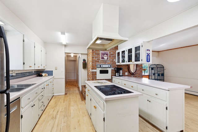 kitchen featuring a center island, white cabinets, light wood-type flooring, appliances with stainless steel finishes, and custom range hood