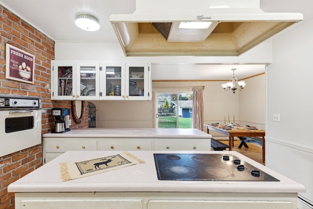 kitchen with brick wall, a notable chandelier, white cabinets, oven, and hanging light fixtures