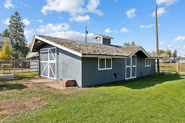 rear view of house with a lawn and an outbuilding