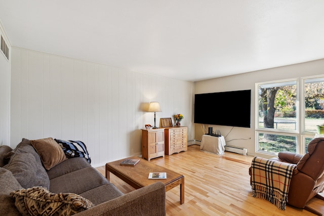 living room featuring wood-type flooring, baseboard heating, and wooden walls