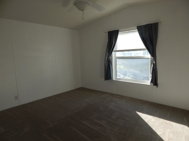 spare room featuring ceiling fan, carpet, and lofted ceiling