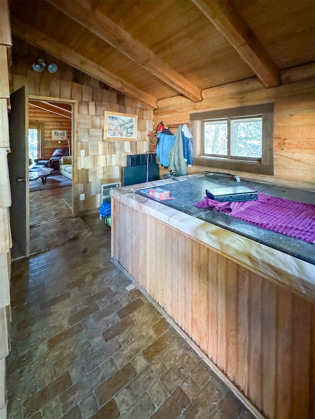 interior space with wooden walls, wooden ceiling, and vaulted ceiling with beams