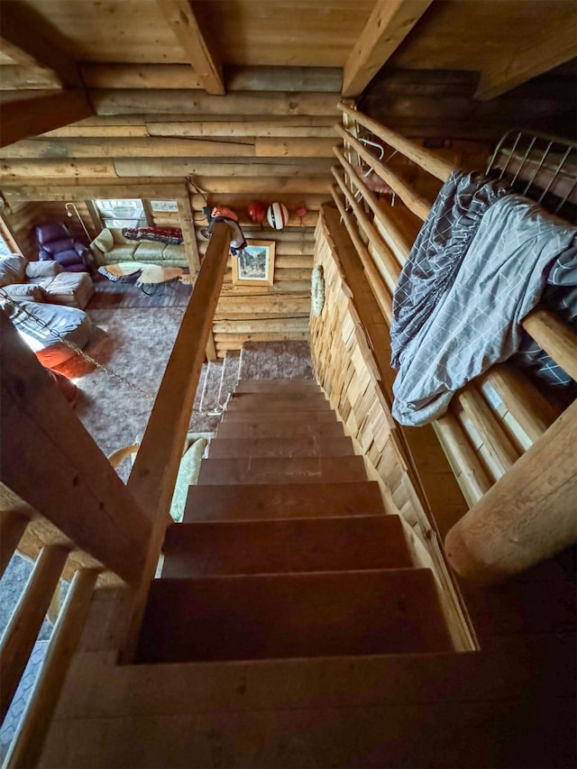 staircase featuring log walls, beamed ceiling, and wood-type flooring