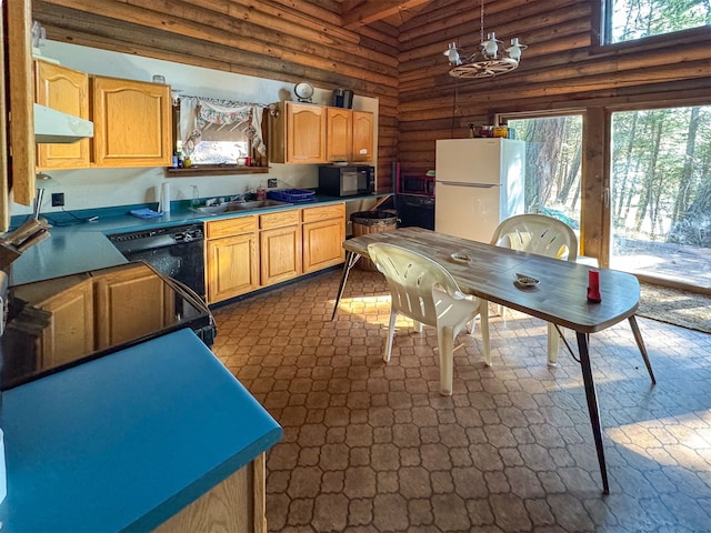 kitchen with a notable chandelier, a healthy amount of sunlight, black appliances, and rustic walls