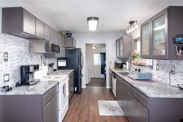 kitchen with sink, dark wood-type flooring, appliances with stainless steel finishes, and decorative backsplash