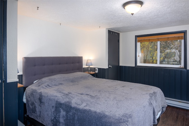 bedroom with a baseboard radiator, dark wood-type flooring, and a textured ceiling