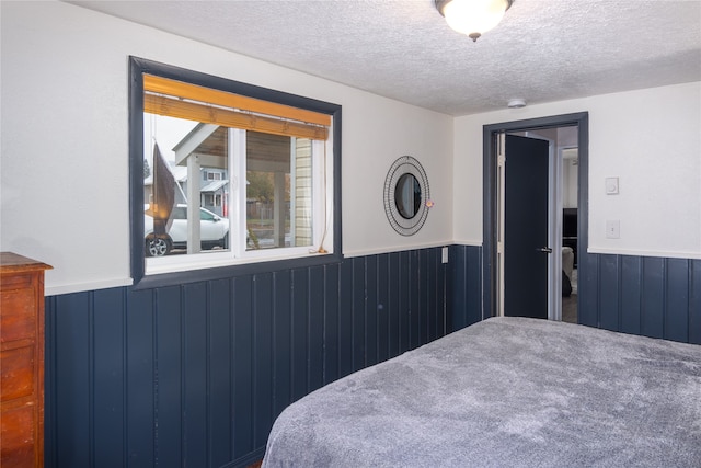 bedroom with wooden walls, a textured ceiling, and carpet floors