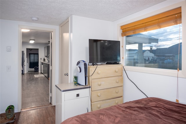 bedroom featuring stainless steel fridge, a textured ceiling, and wood-type flooring