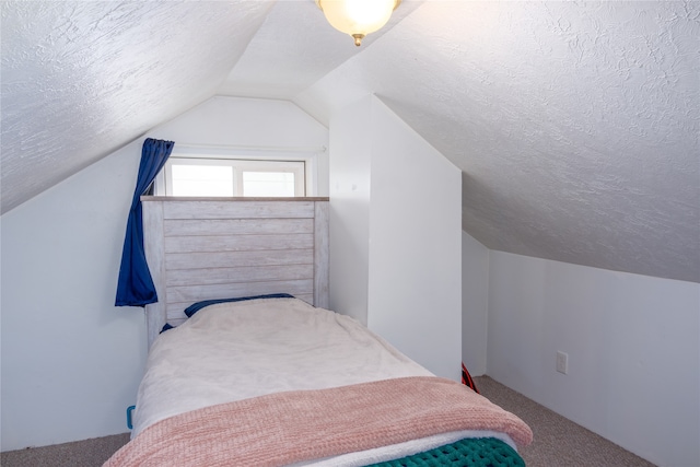 bedroom with lofted ceiling, a textured ceiling, and carpet flooring